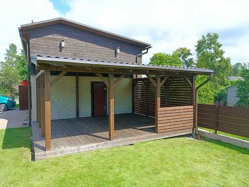 Tumši brūna koka mājai pievienota veranda ar jumtu – 4.8×6 m